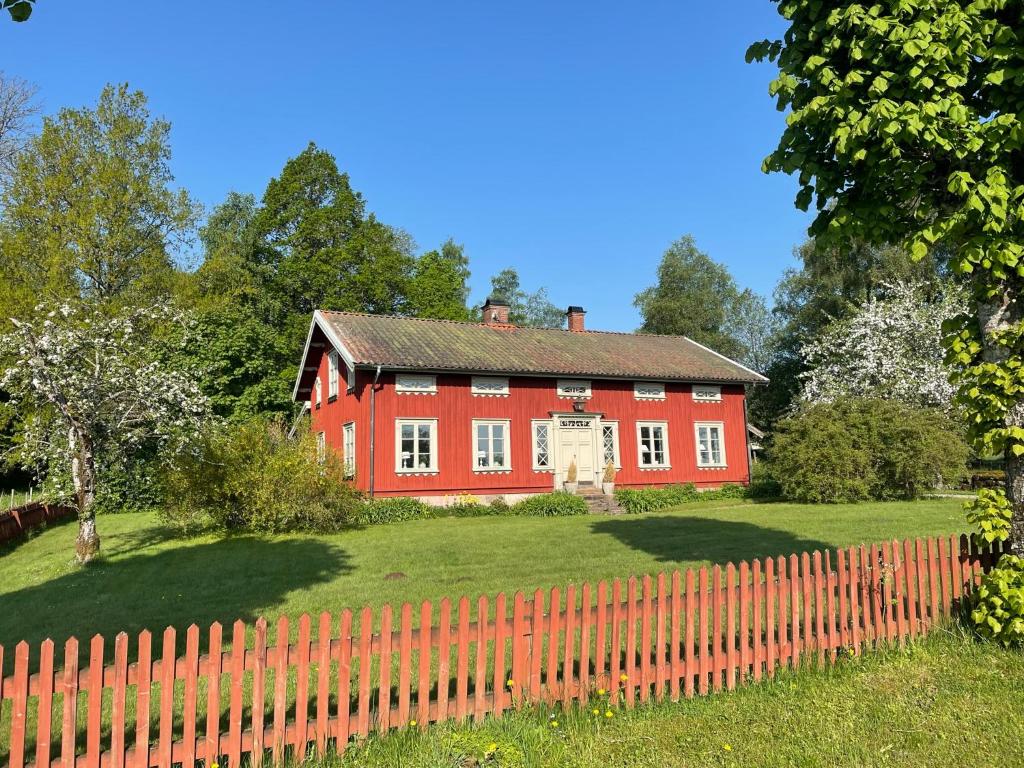 een rood huis met een hek ervoor bij Dalen in Hökerum