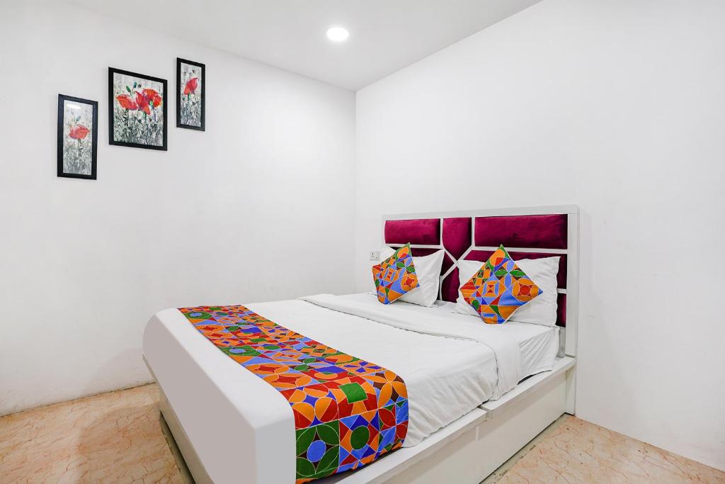 a white bedroom with a bed with colorful pillows at FabExpress VYS Inn in Pune