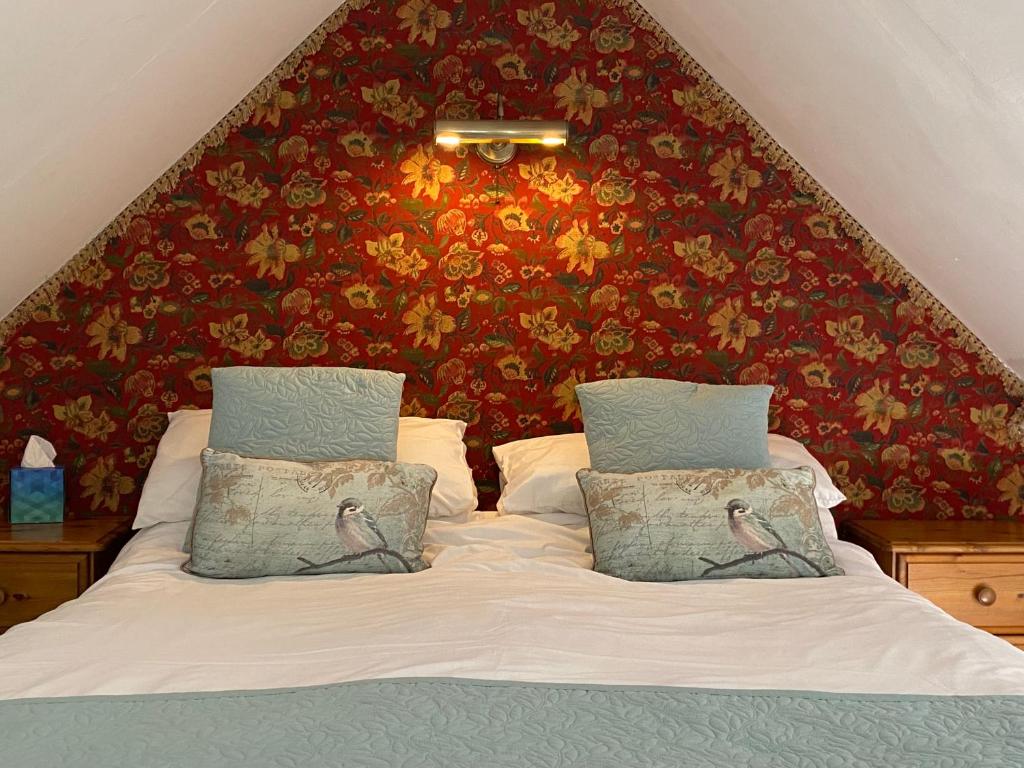 a bedroom with a bed with a red wall at Barnacle Barn, North Norfolk in Roughton