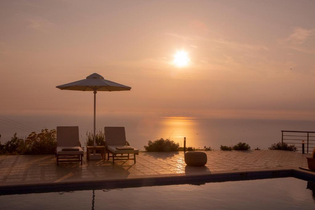 Avraam Sunset Villas with Private Heated Pools by Imagine Lefkada في كالاميتسي: مسبح مع كرسيين ومظلة والمحيط