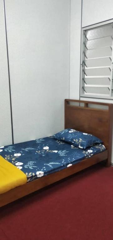 een slaapkamer met een bed met een blauwe sprei en een raam bij Kama BDS Homestay Temerloh in Temerloh