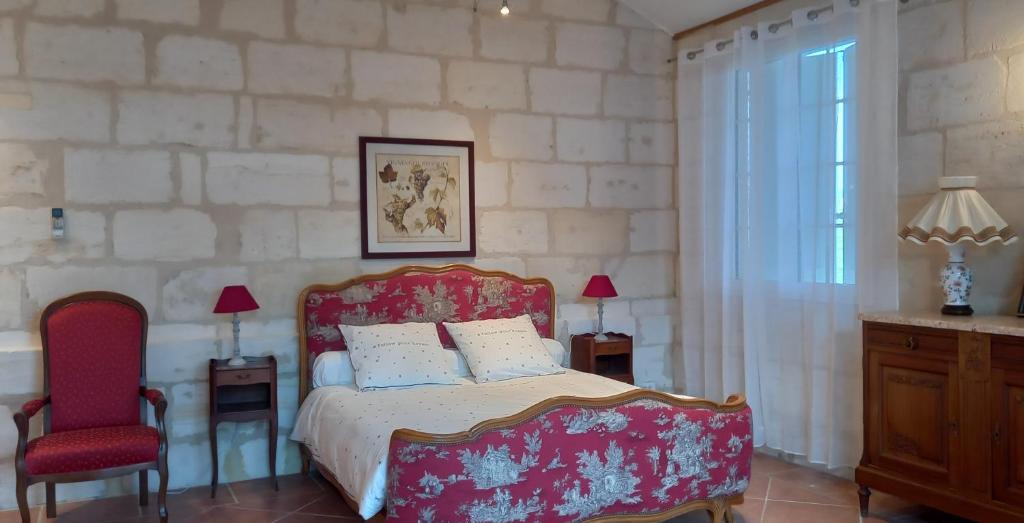 ein Schlafzimmer mit einem Bett und einem roten Stuhl in der Unterkunft L'HERMITAGE D'ALIENOR in Lugon et l’Ile du Carney