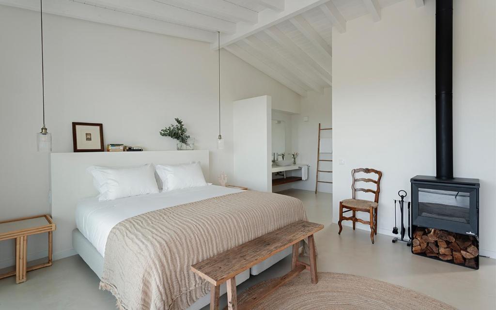 a bedroom with a bed and a fireplace and a chair at Amaria in Aljezur