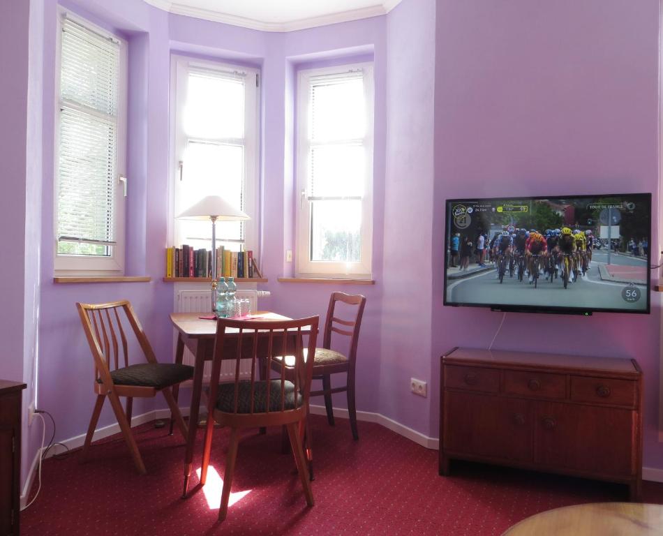 a dining room with purple walls and a table with a television at Die große Wohnung in Droyßig
