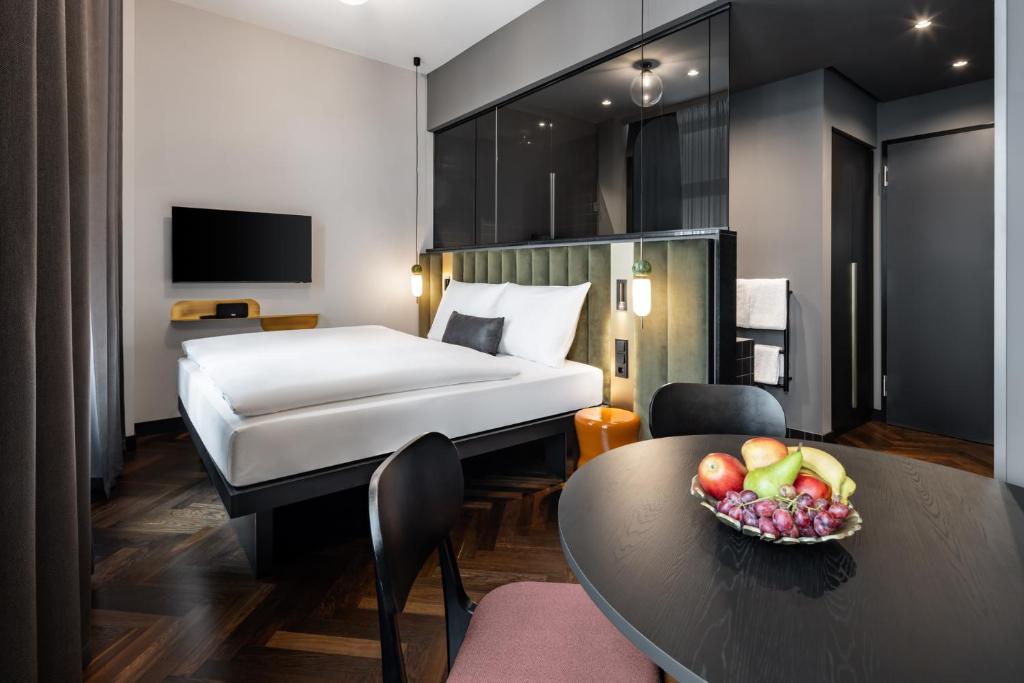 una habitación de hotel con una cama y un bol de fruta en una mesa en AMANO Home Leipzig en Leipzig