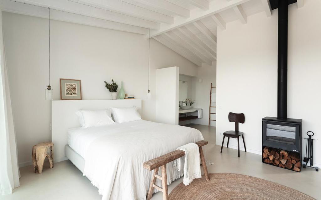 a white bedroom with a white bed and a fireplace at Amaria in Aljezur