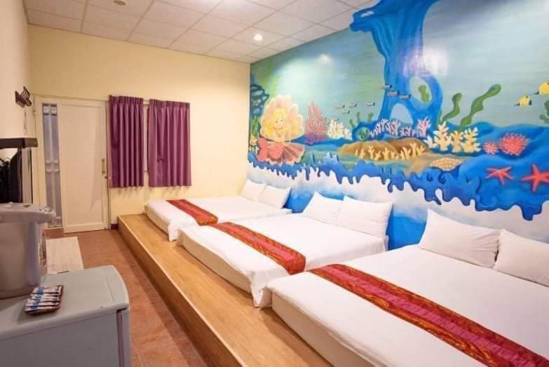 a room with three beds with a painting on the wall at Fumigate Hotel in Hengchun South Gate