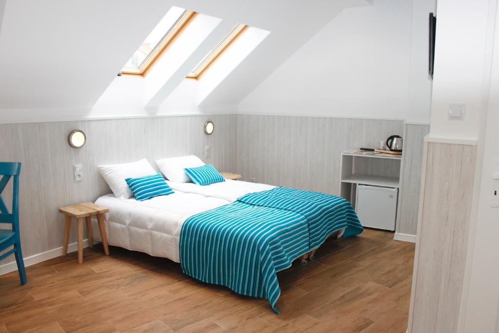 1 dormitorio con 1 cama con sábanas azules y blancas en Pensjonat Orka Mielno, en Mielno