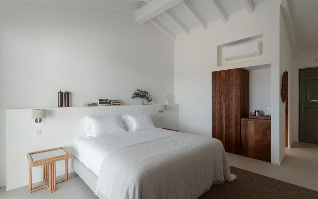 a white bedroom with a white bed and a wooden cabinet at Amaria in Aljezur