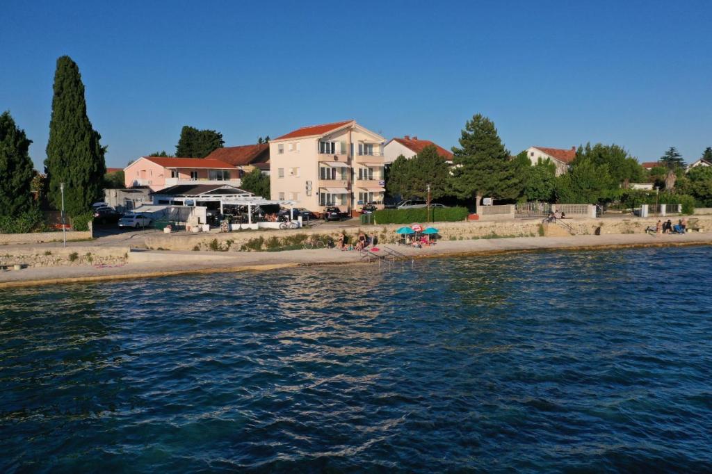 a body of water with a beach and buildings at Apartments Lara in Sukošan