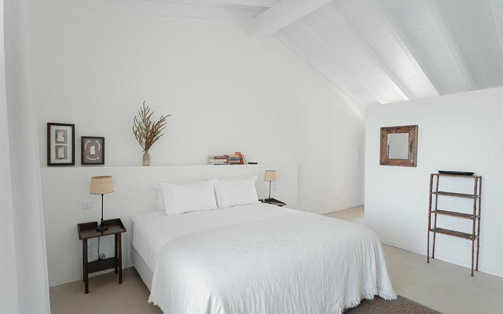 a white bedroom with a white bed and a ladder at Amaria in Aljezur