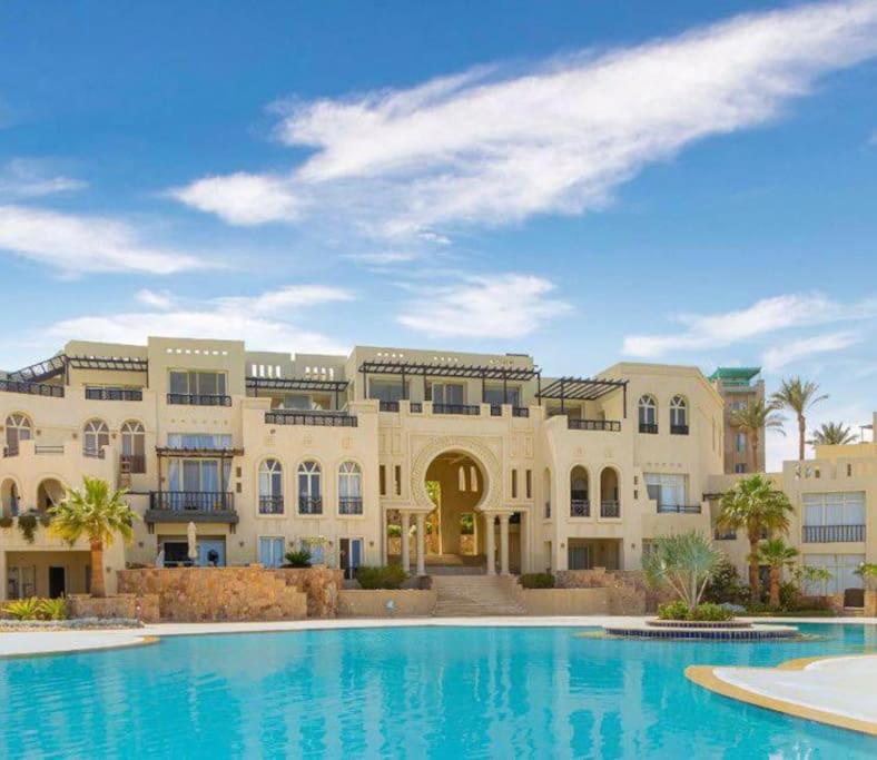 een groot gebouw met een zwembad ervoor bij Azzurra two-bedrooms apartment at Sahl Hasheesh in Hurghada