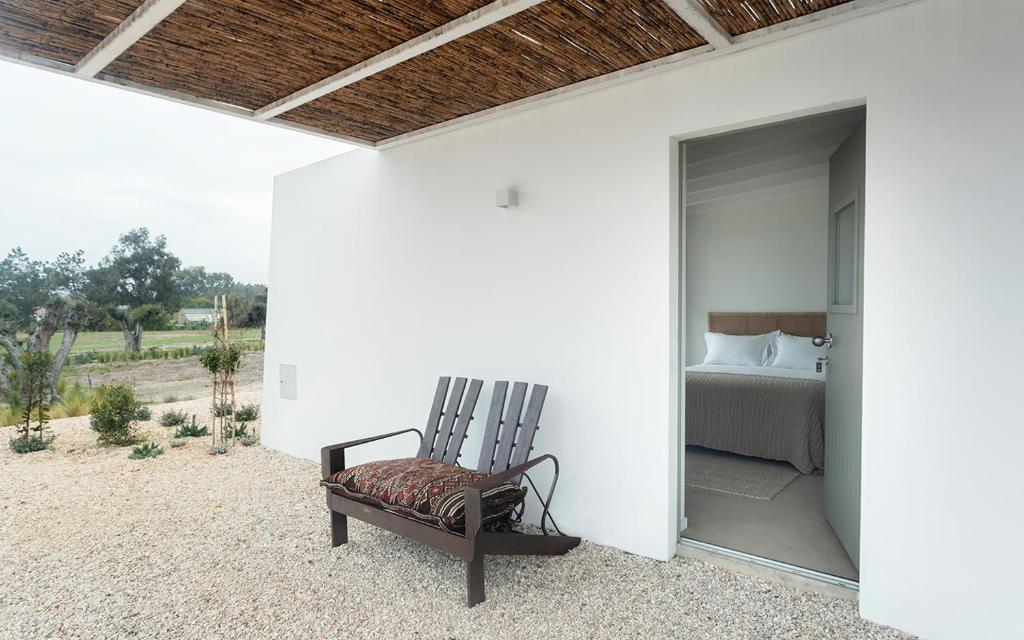 a room with a bed and a chair on a patio at Amaria in Aljezur
