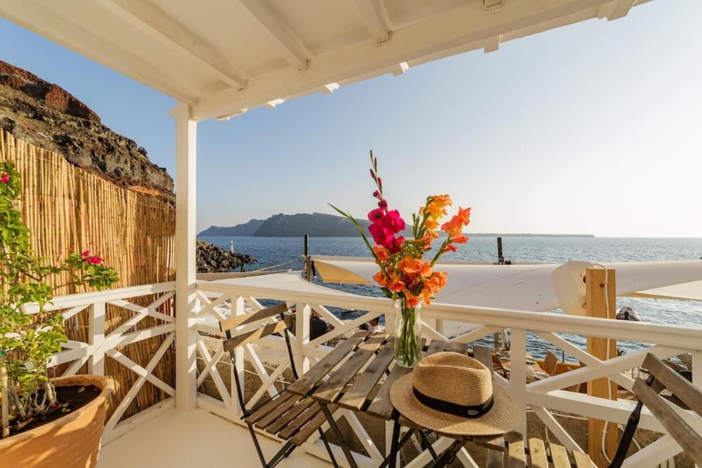 a table with a vase of flowers on a balcony at The Bay - Loft apartment Sea & Sunset View in Oia