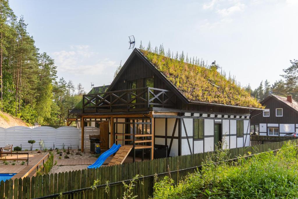 a house with a grass roof with a playground at Domek Na Gwizdówce " u KARGULA" - KASZUBY in Sierakowice