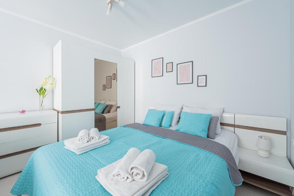 a bedroom with a blue bed with towels on it at Apartament z balkonem przy Latarni 150m od morza in Kołobrzeg