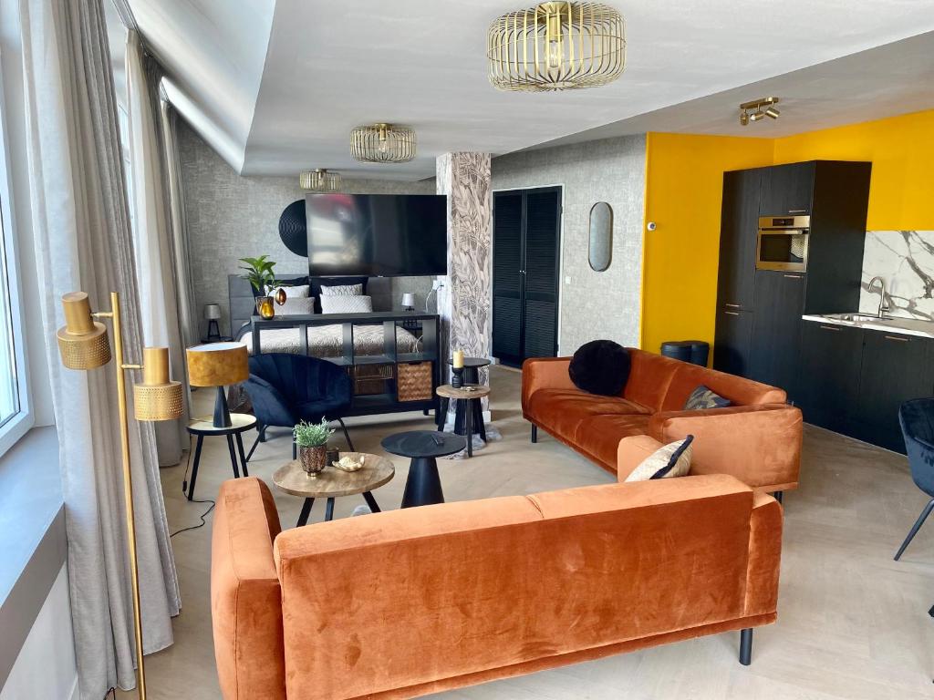 een woonkamer met oranje meubels en gele muren bij Glücklich am Meer Suite Deluxe mit Wellnesszugang in Egmond aan Zee