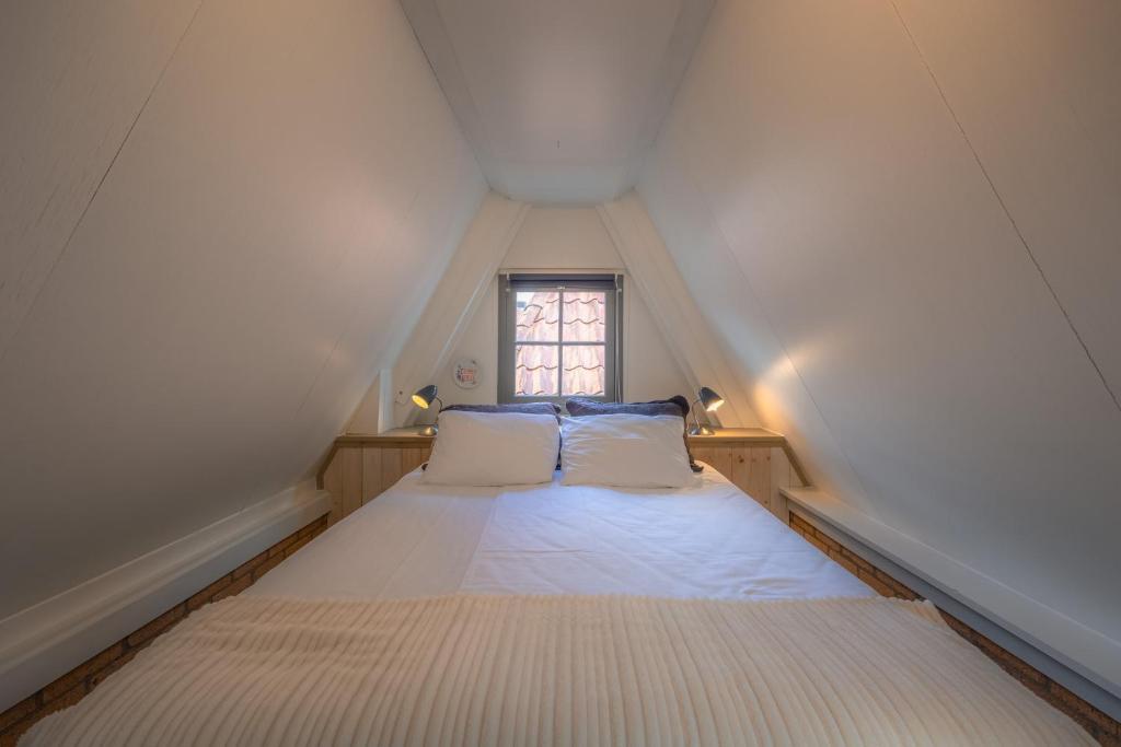 een kleine slaapkamer met een bed op zolder bij Gasthuis Dokkum in Dokkum