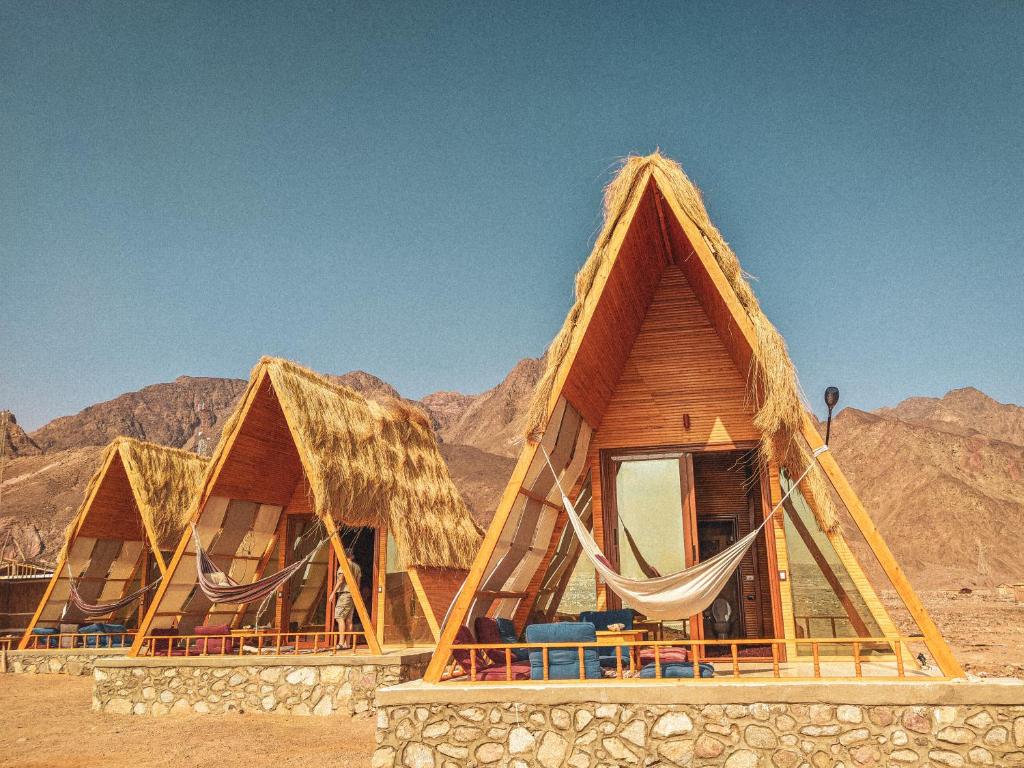 a row of huts in the desert with mountains at Aladdin Camp in Nuweiba
