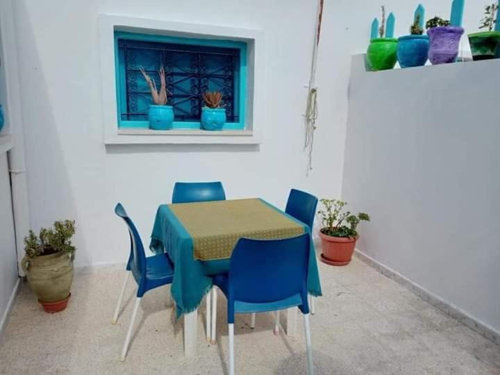einen Tisch und Stühle mit einem blauen Tisch und einem Fenster in der Unterkunft Bungalow de charme in Midoun