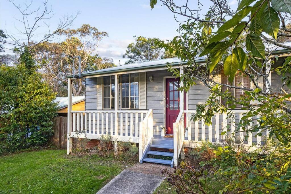 ein kleines Haus mit einer roten Tür und einer Veranda in der Unterkunft Blissful Mountain Stay in Katoomba