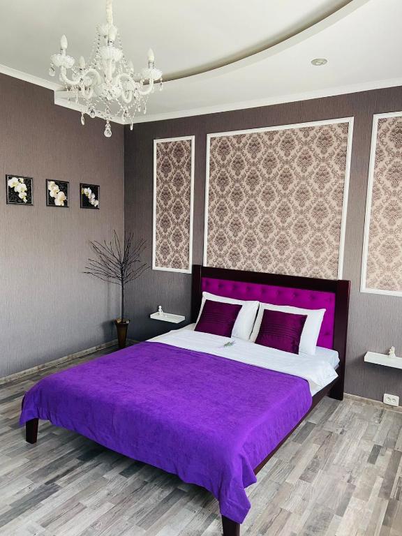 1 dormitorio con cama morada y lámpara de araña en Готель Лаванда на Ривьере , Карпатский чан, Фонтанка 1 Одесса en Fontanka