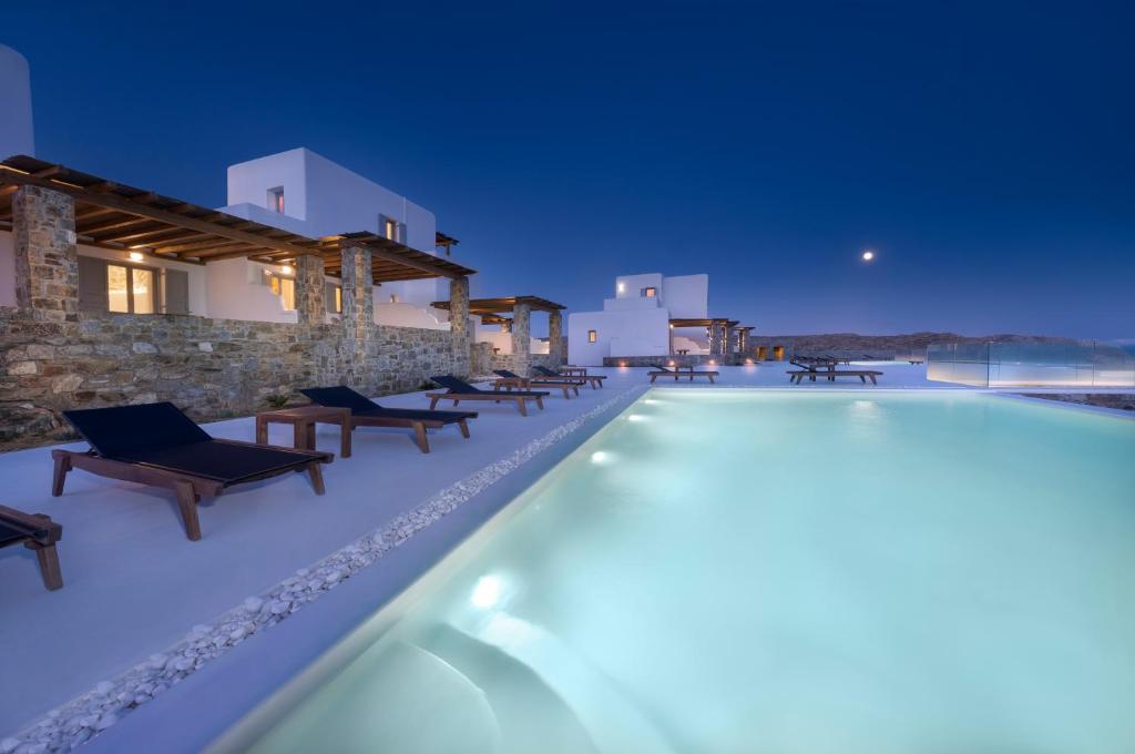 een zwembad met stoelen en een gebouw bij Legendary Suites in Mykonos-stad