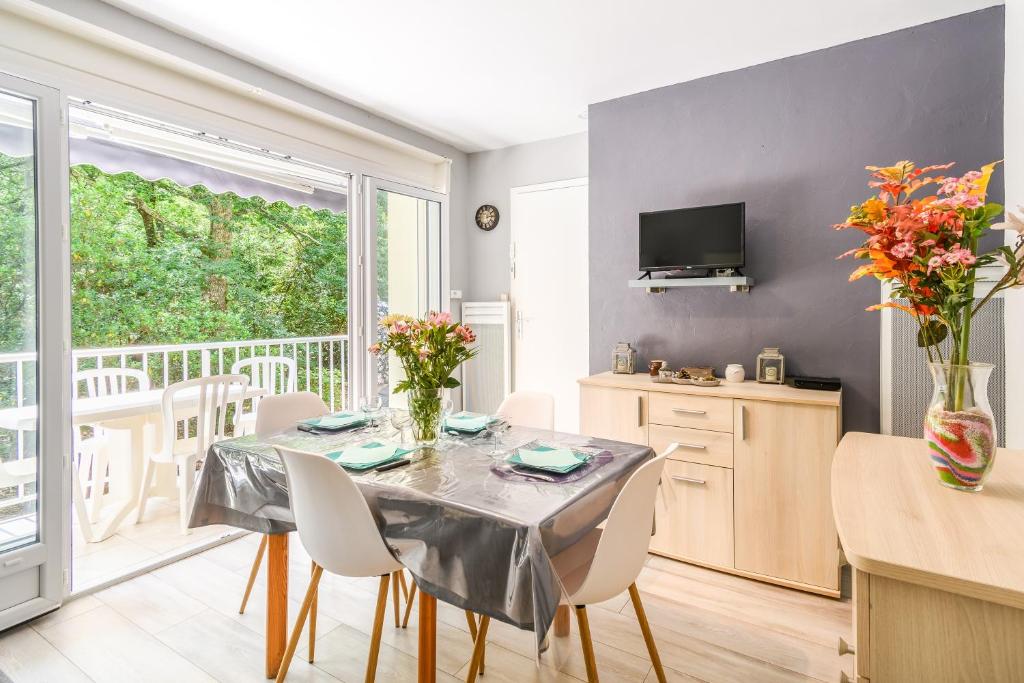 une salle à manger avec une table et des chaises et un balcon dans l'établissement Pot de Résine - Appartement à 500m de la plage, à Arcachon