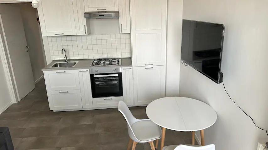 uma cozinha com armários brancos, uma mesa e um lavatório em Galvani 11 em Parma
