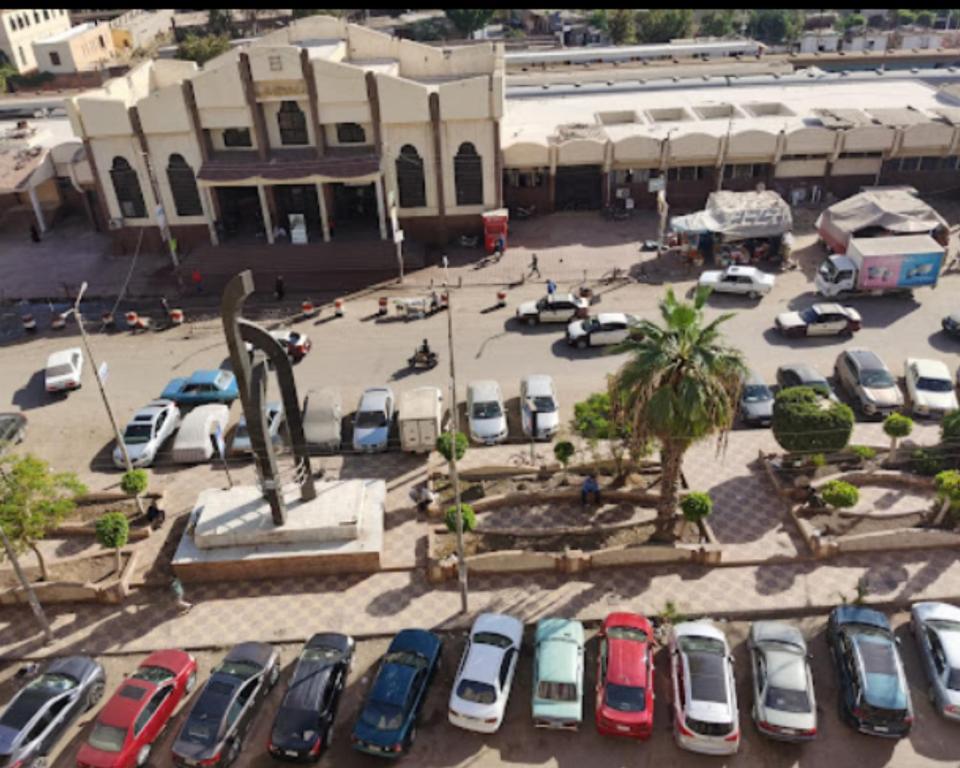 a parking lot with cars parked in front of a building at Salvatore Rooms With Breakfast -Train Station in Mansoura
