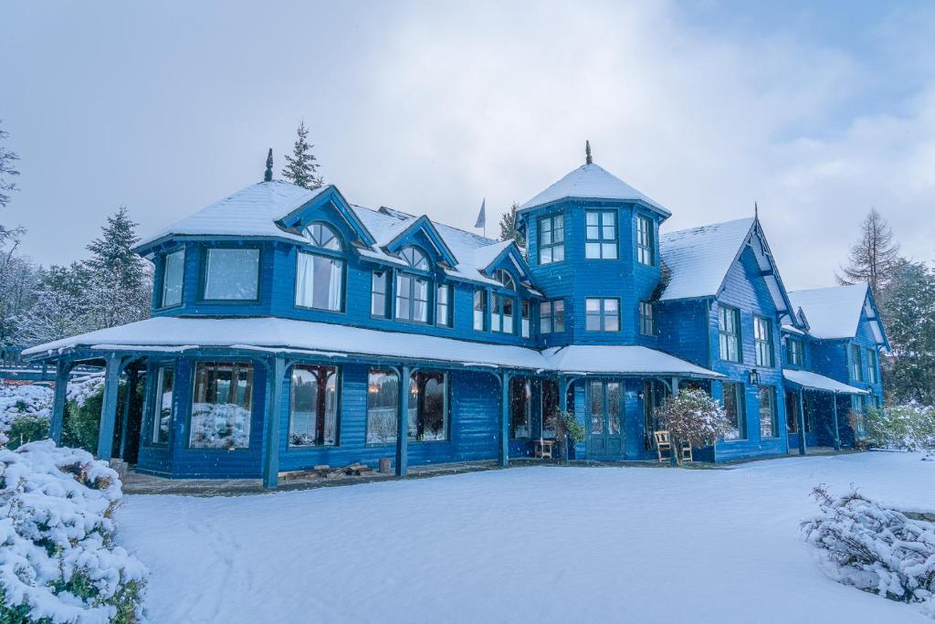 ein großes blaues Haus mit Schnee drauf in der Unterkunft Las Balsas Relais & Chateaux in Villa La Angostura