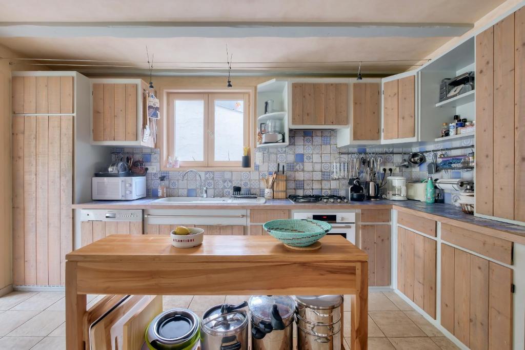 a kitchen with wooden cabinets and a wooden table at Havre de paix pour 10 a l Ile de Re in La Flotte