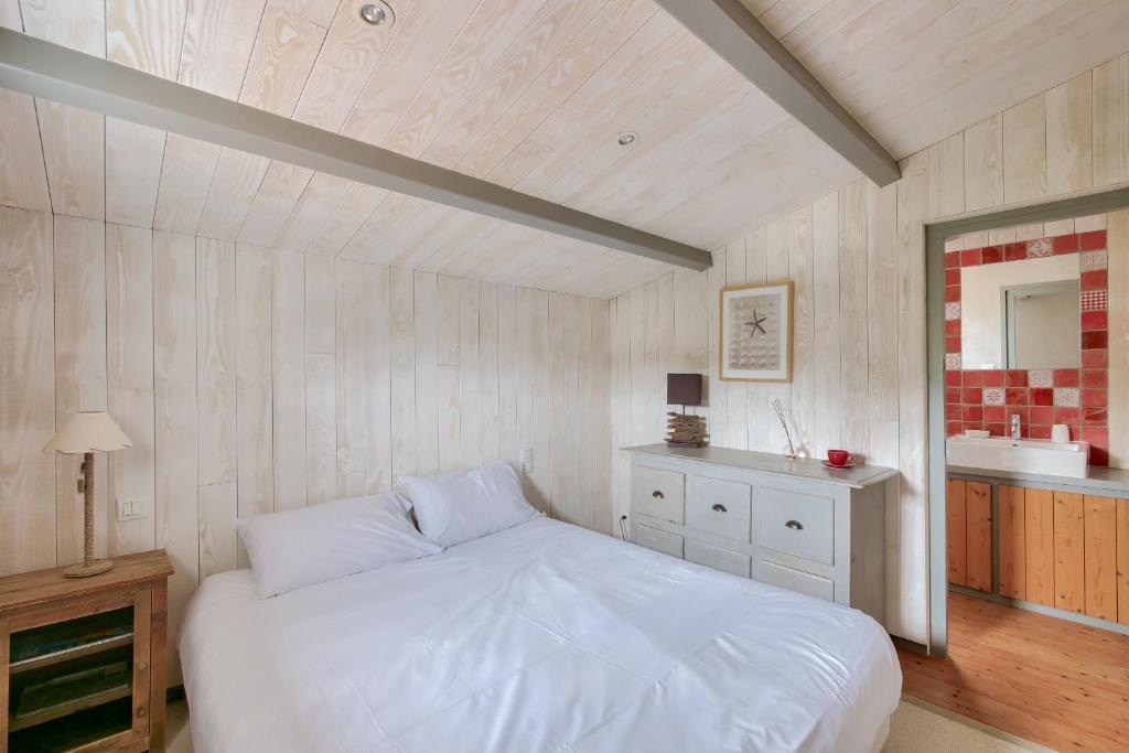 a bedroom with a white bed and a sink at Havre de paix pour 10 a l Ile de Re in La Flotte