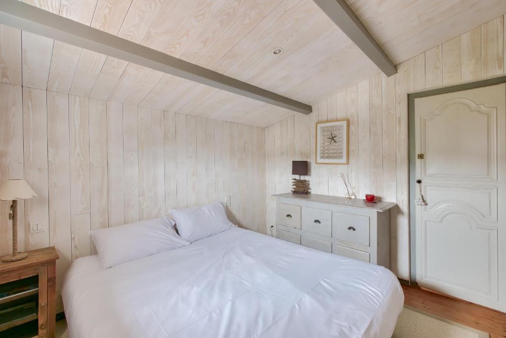 a bedroom with a white bed and a white door at Havre de paix pour 10 a l Ile de Re in La Flotte