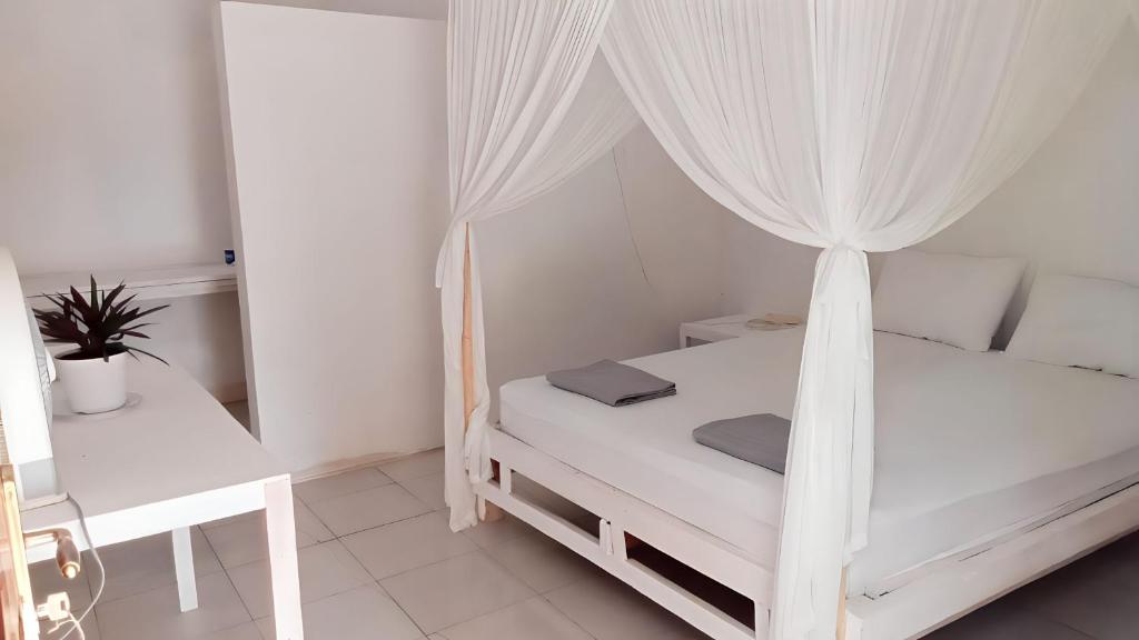 the village rua beach homestay في Rua: غرفة نوم بيضاء مع سرير مع مظلة