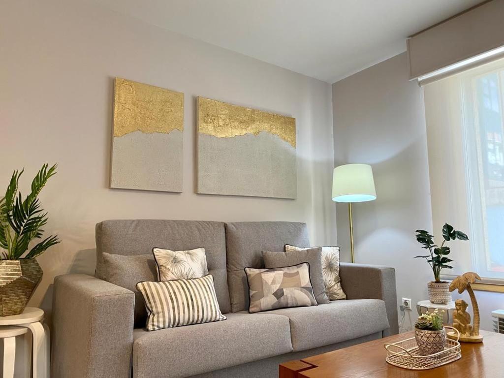 a living room with a couch and paintings on the wall at Andainas G in Milladoiro