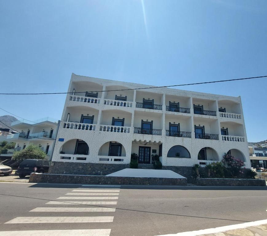 Un grand bâtiment blanc avec balcon se trouve dans une rue. dans l'établissement Corali Studios & Portobello Apartments, à Elounda