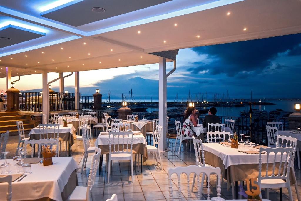 restauracja z białymi stołami i krzesłami oraz widokiem na ocean w obiekcie La Sciabica w Agropoli
