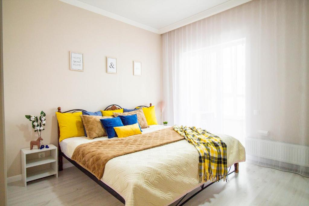 a bedroom with a bed with yellow and blue pillows at AB Apart Comfort 5311 in Astana