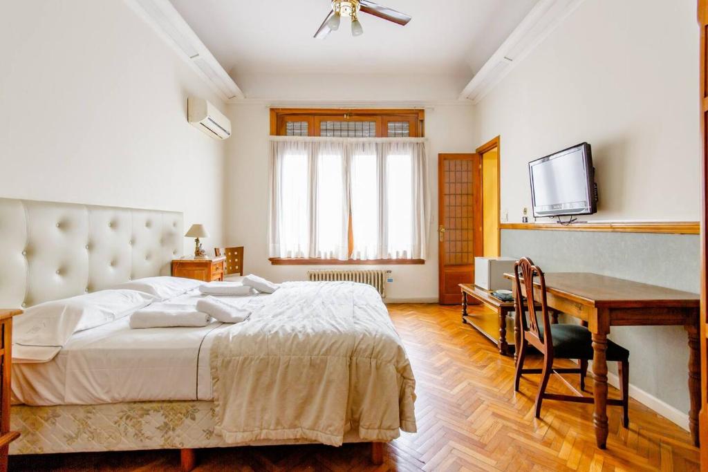 Dormitorio con cama, escritorio y TV en Baires House en Buenos Aires