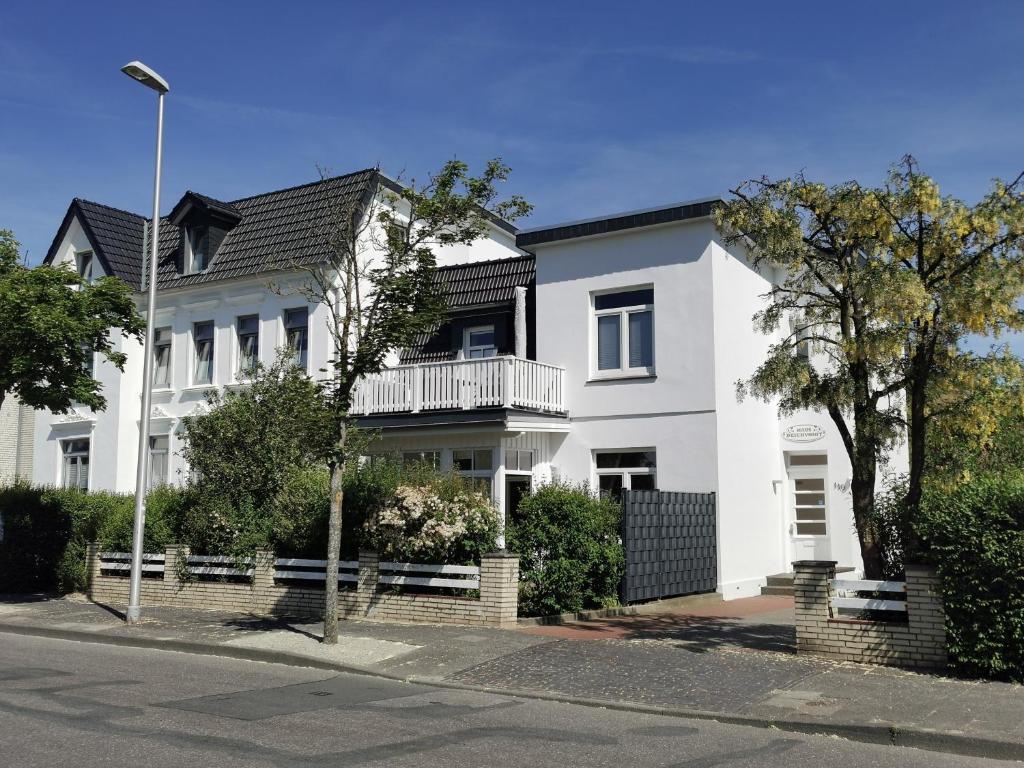 a white house with a balcony on a street at Haus Deichvoigt in Cuxhaven