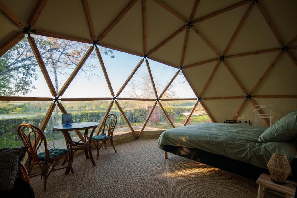 - une chambre avec un lit et une table dans une tente dans l'établissement Dôme avec vue sur Loire proche de Chambord, à Saint-Dyé-sur-Loire