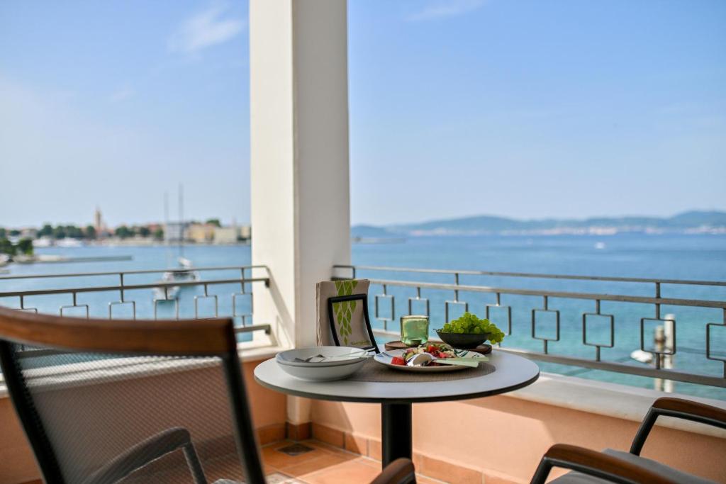 a table with a plate of food on a balcony at Villa Hrešć S in Zadar