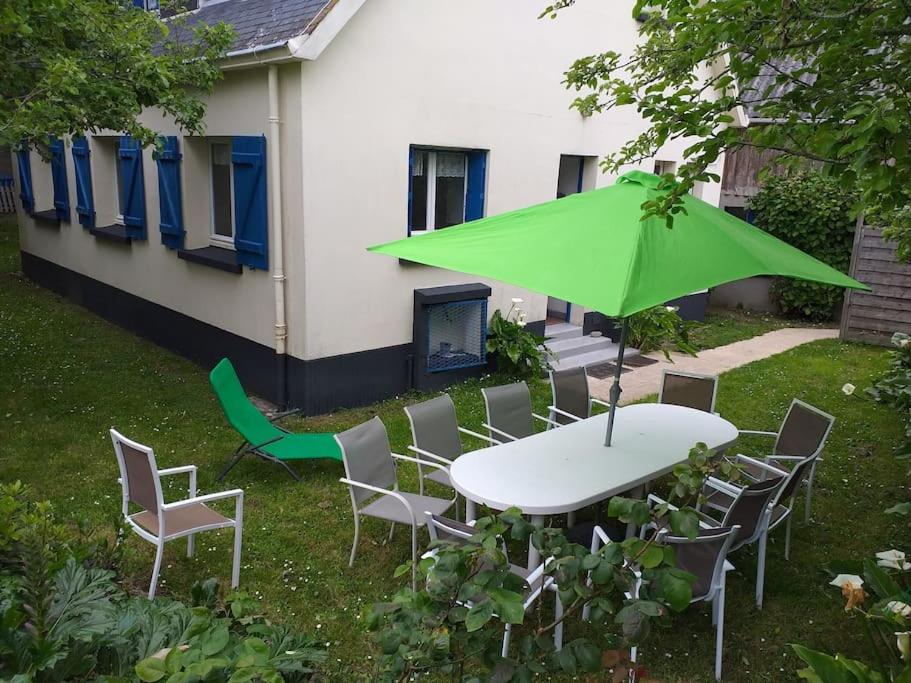 une table et des chaises avec un parasol vert dans l'établissement Kerleuquer Ty Nevez, à Plobannalec-Lesconil