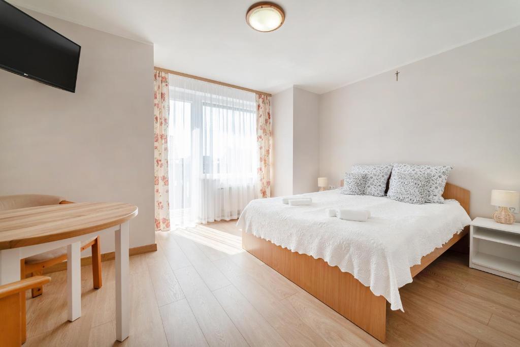 a white bedroom with a bed and a window at Nord Jastarnia in Jastarnia