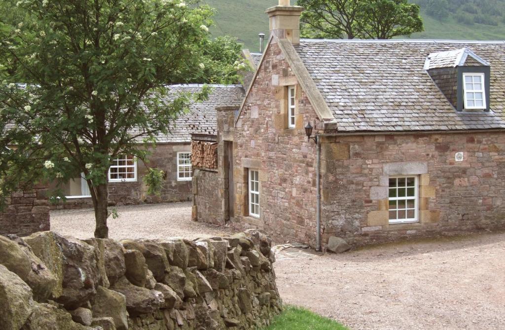 ein altes Steinhaus mit einer Steinmauer in der Unterkunft Eastside Byre - Family cottage in the Pentland Hills near Edinburgh in Penicuik
