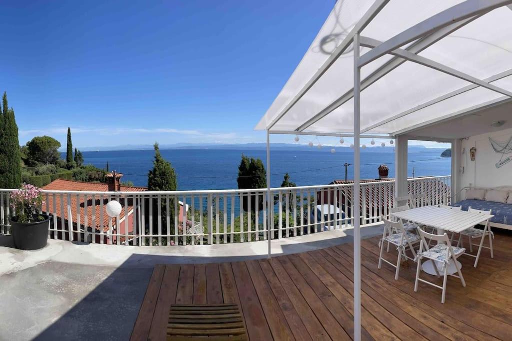 eine Terrasse mit einem weißen Regenschirm, einem Tisch und Stühlen in der Unterkunft Sunrise SeaView Apartment Fiesa in Piran