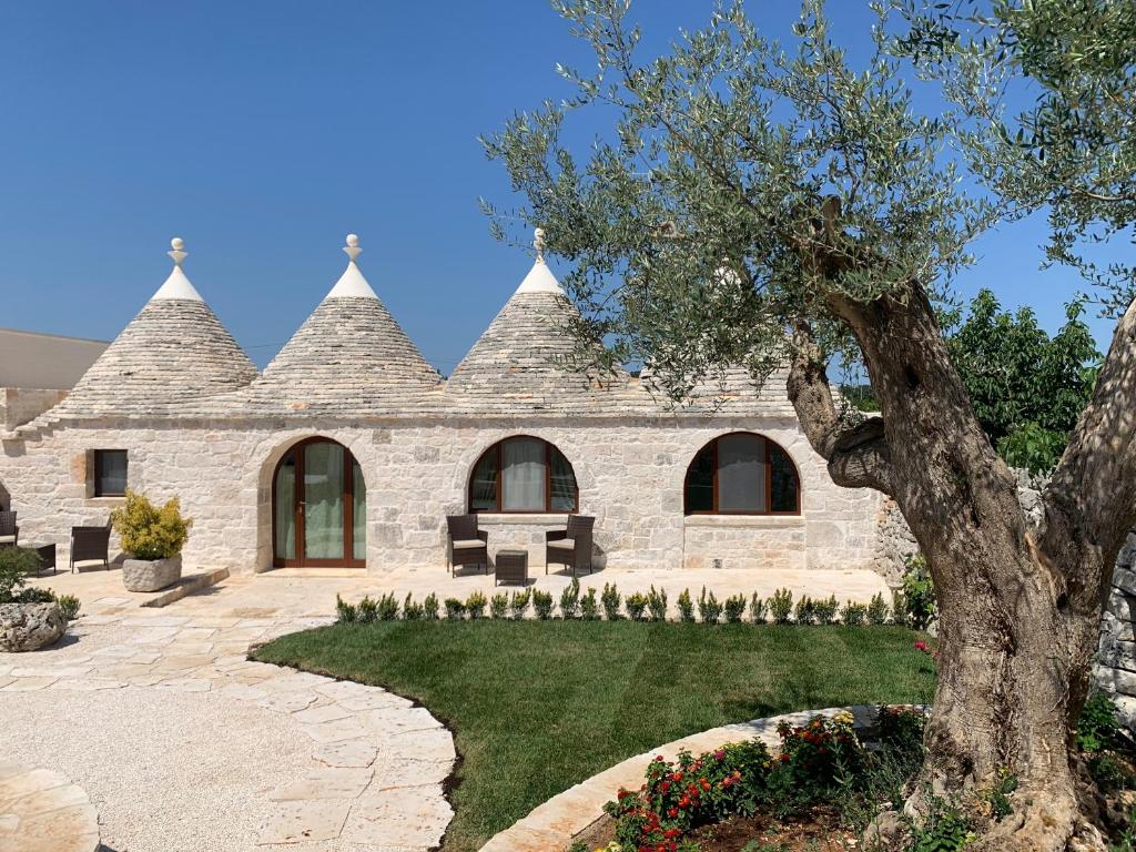 une maison en pierre avec un arbre dans la cour dans l'établissement Agli Antichi Trulli B&B In Masseria, à Alberobello