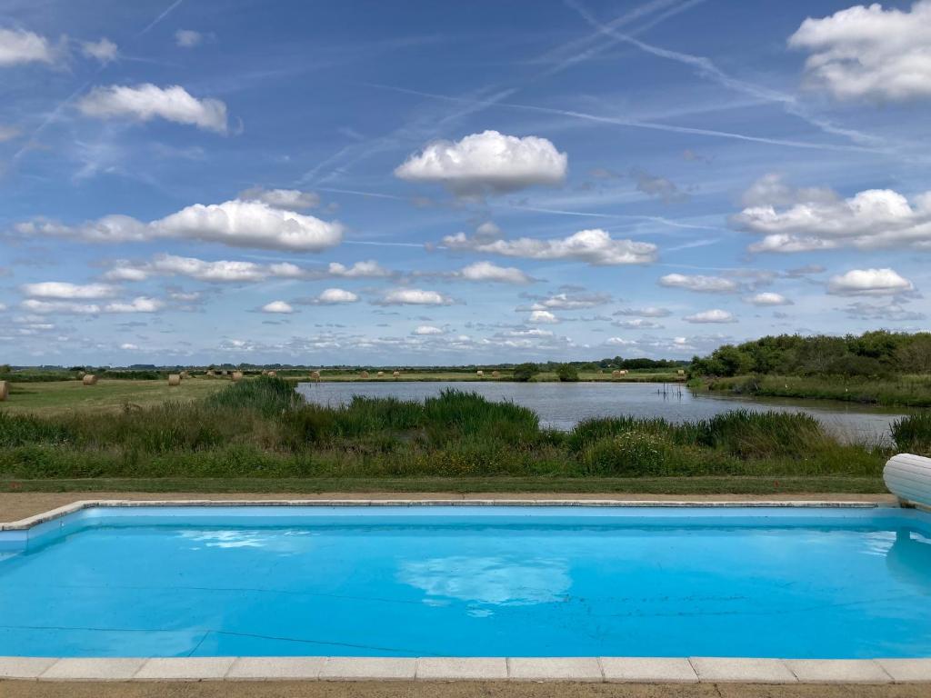 a swimming pool with a view of a river at Au cœur du marais breton in Bois-de-Cené