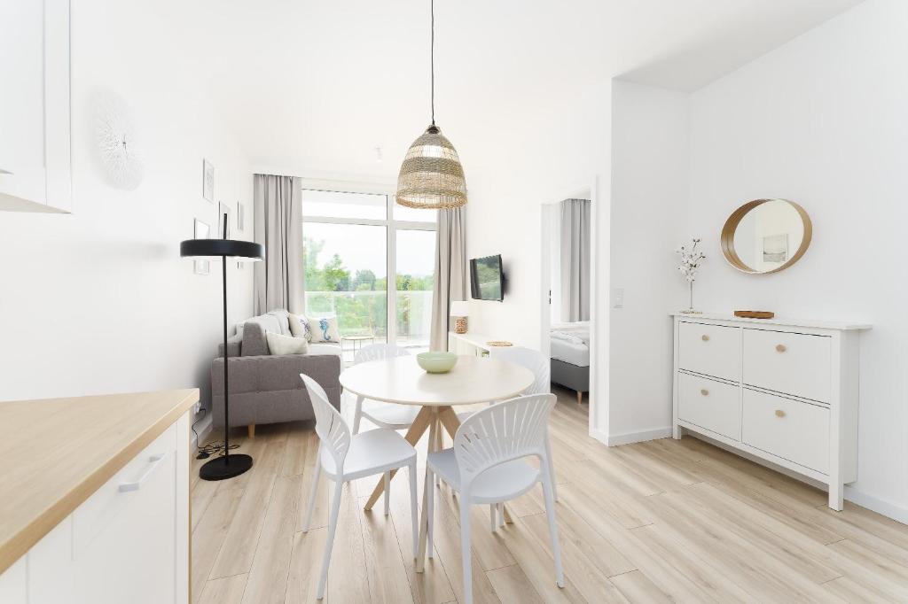 Una cocina y una sala de estar con mesa y sillas. en Apartament Perłowy z Basenem Letnim by HolidaySun, en Sianożęty